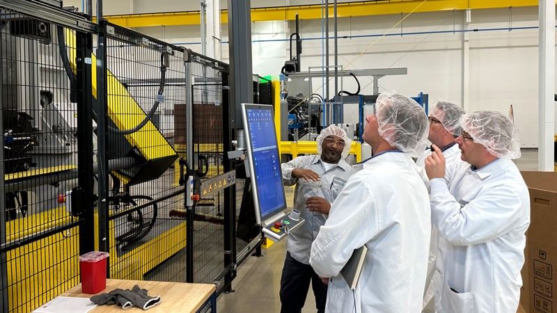 food production engineers talking with machine operator