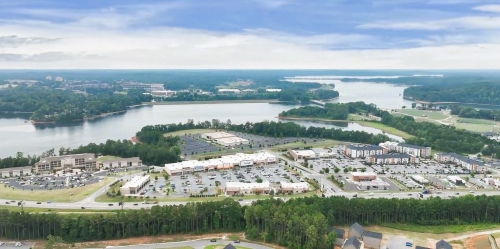 aerial view of a retail shopping complex located next to a river and outlined by trees